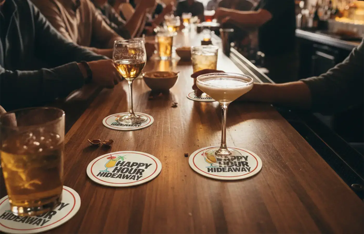 Happy hour drinks on a bar counter, each glass placed on printed drink coasters promoting a bar's happy hour special.