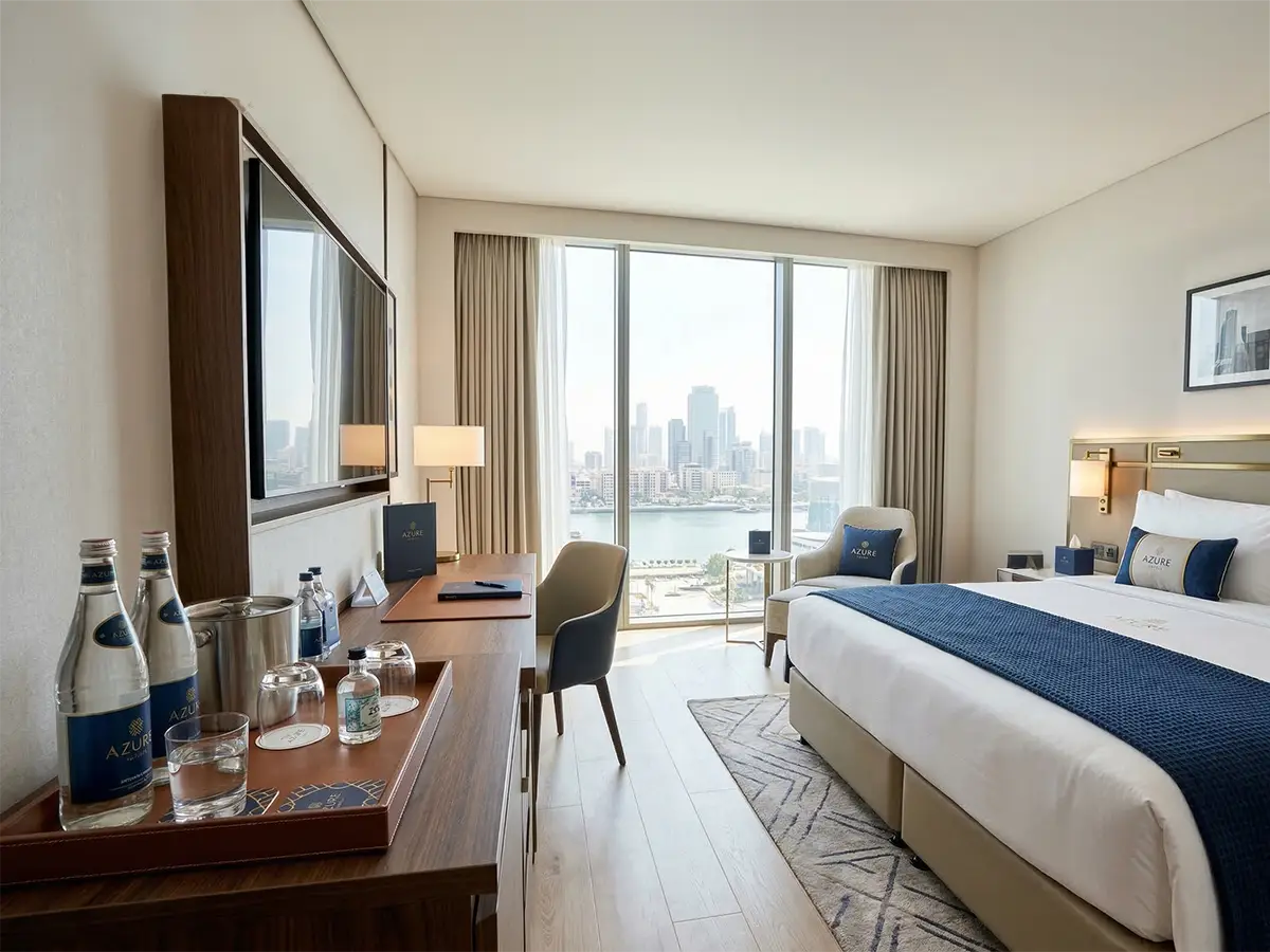 Modern hotel room with minibar tray featuring drinks on branded coasters.