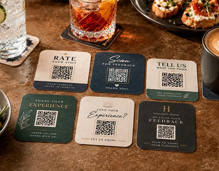 Set of custom QR code coasters with feedback messages displayed on a restaurant table with drinks and appetizers.